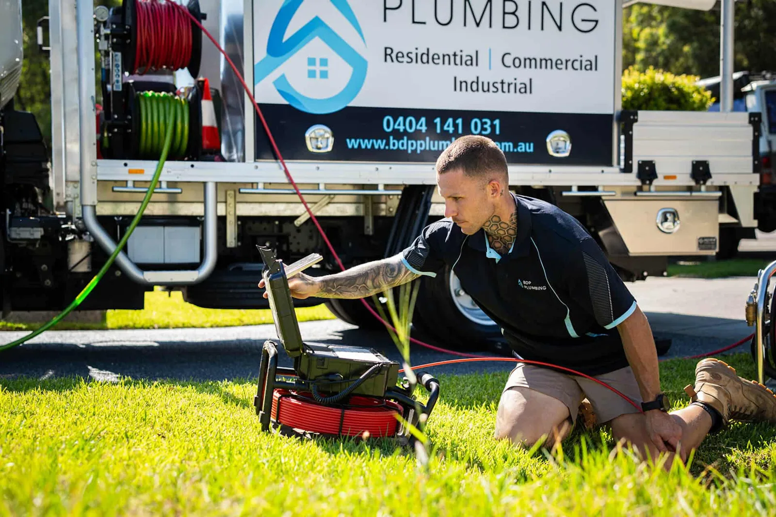 Plumber running a CCTV drain camera beside the truck